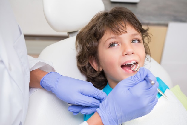 pediatric-dentist-examining-little-boys-teeth-dentists-chair_13339-298672