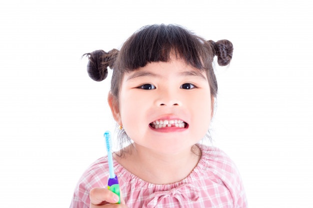 little-asian-girl-holding-toothbrush-smiles-white-background_34054-460